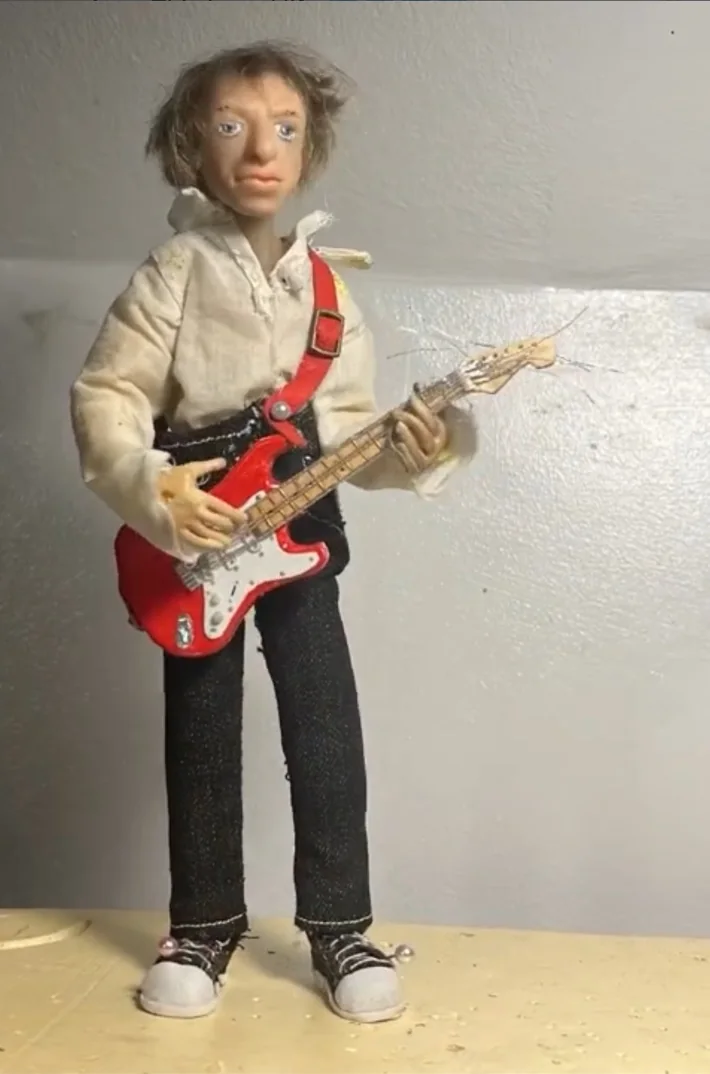 Guitarist puppet standing with a red electric guitar