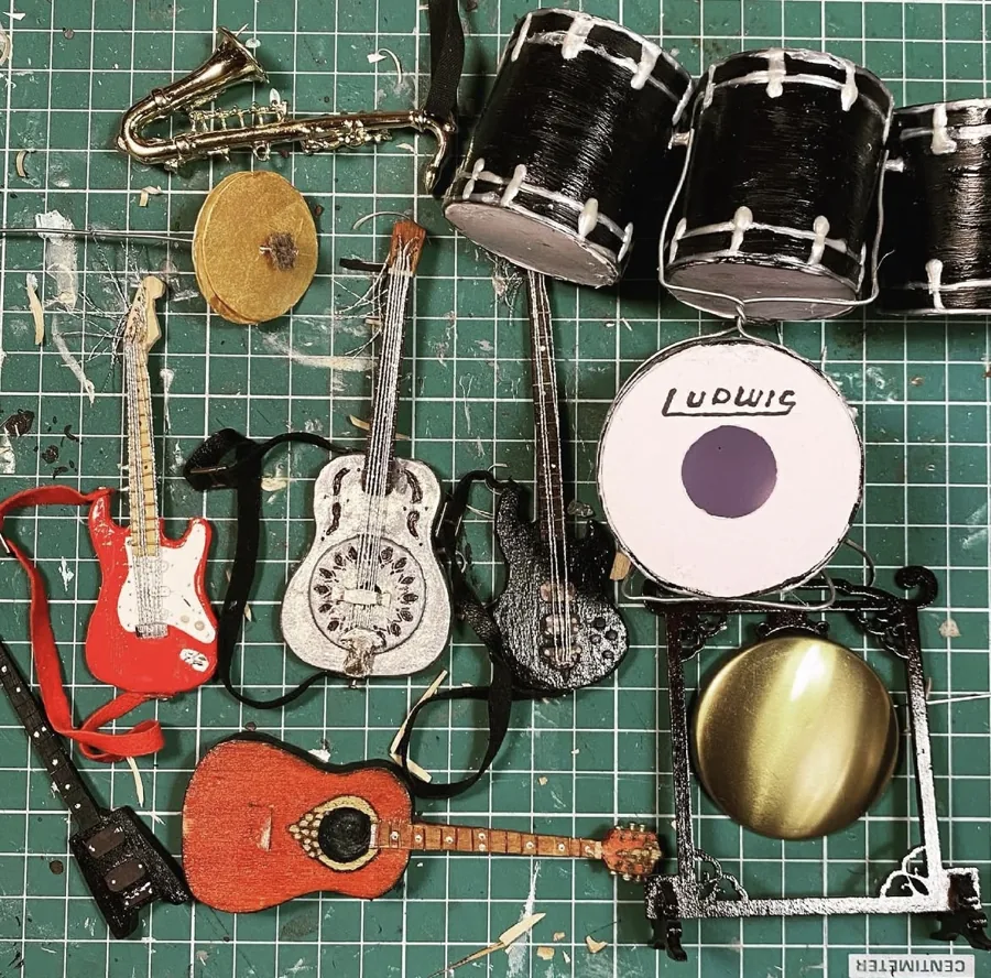 Handmade miniature guitars, saxophone and drum kit laid out on a cutting mat