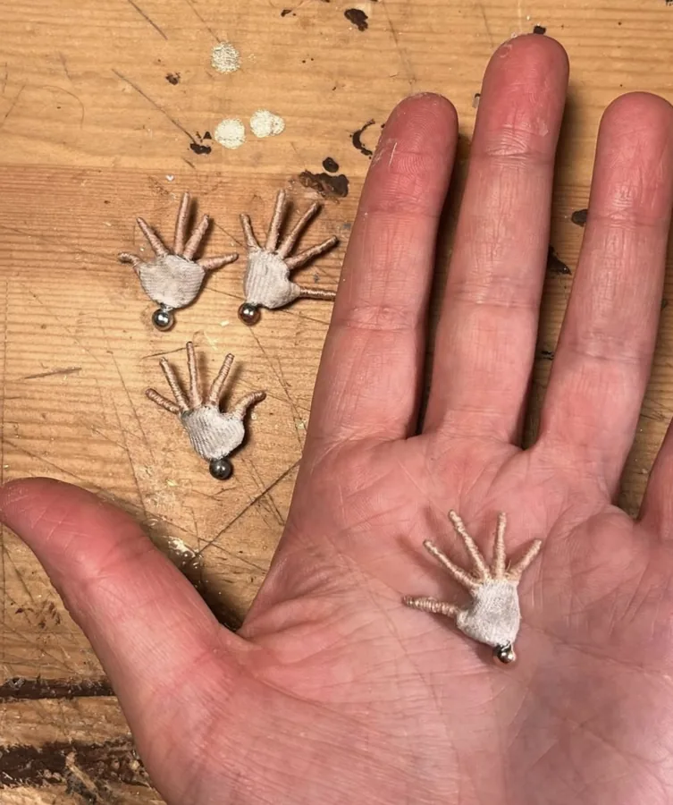 Tiny puppet hands beside a human hand