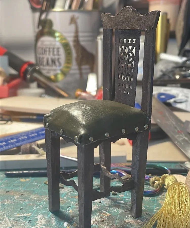 A miniature chair with a leather-upholstered seat